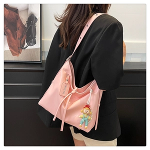 Pink crescent hobo bag with drawstring detail and cute doll pendant on a model