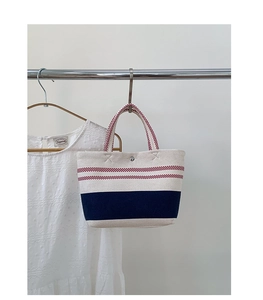 Detail of canvas beach tote with red and navy stripes hanging on a metal rack