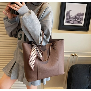 Detail of dark brown leather tote bag with elegant geometric pattern scarf accessory