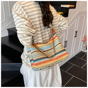 Detail of colorful woven shoulder bag featuring a striped pattern and metal chain strap