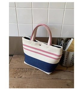 Detail view of tri-color canvas tote bag featuring reinforced blue base and metal snap button