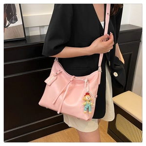 Detailed close-up of pink faux leather hobo bag with fringe drawstring and adjustable strap