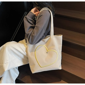 Détail du sac fourre-tout en toile crème avec imprimé cœur jaune et décoration en métal