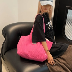 Vue d'épaule du grand sac cabas rose fuchsia en toile matelassée avec étiquette latérale