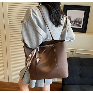 Detail view of brown leather tote bag with geometric silk scarf handle decoration