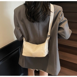 Dettaglio di borsa a tracolla beige in pelle sintetica con zip e borchie laterali