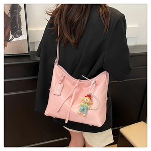 Detail of pink leather tote bag with cute doll charm and adjustable shoulder strap