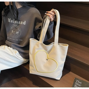 Sac fourre-tout en toile avec cœur jaune posé sur un escalier en bois authentique