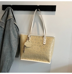 Vue détaillée du cabas beige avec motifs de dessins animés gaufrés et texture cuir