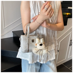 Detail of silver textured mini bucket bag with a cute plush bear charm accessory