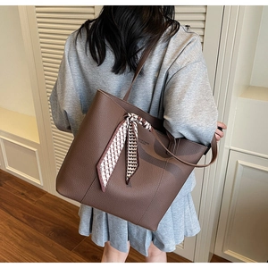 Detail view of large dark brown leather tote bag with silk scarf on the handle