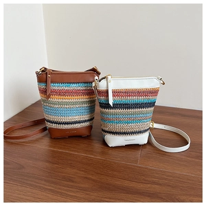 Detail of colorful rainbow woven straw crossbody bags with leather trim on wood