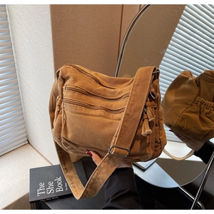 Detail view of brown canvas messenger bag with multi-zipper pockets and wide strap