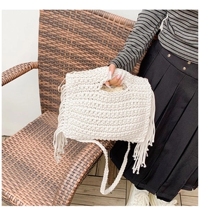 Detail of white crochet tote bag with fringe tassels and woven shoulder strap