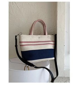Close-up of canvas beach tote with red stripes, woven handles and adjustable strap
