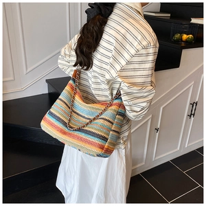 Close-up of colorful striped crochet hobo bag with metal chain and leather shoulder strap