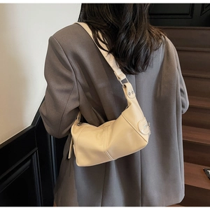 Dettaglio borsa a spalla in pelle crema con fibbia argento su un blazer grigio