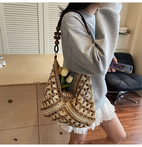 Detail of woven straw tote bag with intricate diamond patterns and wooden bead strap