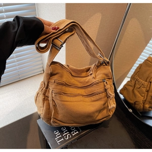 Detail of brown canvas crossbody bag with multi-layer zipper pockets and adjustable strap
