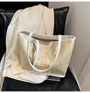Détail du sac cabas crème avec motifs de chiots gaufrés, présenté sur une chaise en cuir