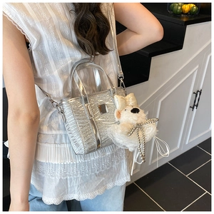 Silver sequin bucket bag featuring a white plush animal charm with lace dress detail