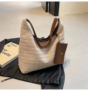 Detail of cream straw tote bag featuring brown leather strap and small detachable pouch