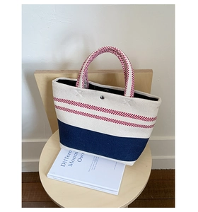 Detail of canvas tote bag showing striped pattern with navy blue bottom and metal snap button