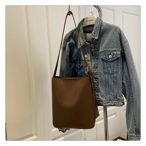 Brown faux leather shoulder bag displayed against a denim jacket for a casual summer style