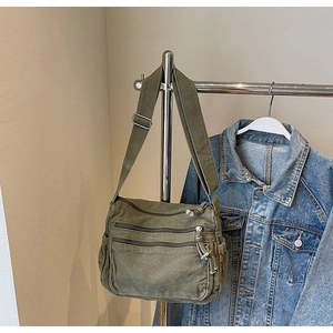 Detail of army green canvas tote bag with multi-zipper pockets and adjustable strap