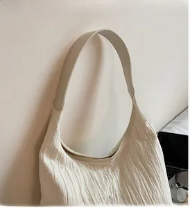 Dettaglio della borsa tote a pieghe bianco sporco con ricamo blu e manico liscio