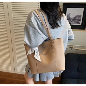Back view of a large camel leather tote bag with silk scarf on a female model