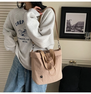 Close-up of beige nylon tote bag with drawstring closure and metallic logo detail