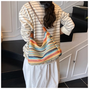Detailed back view of a colorful striped woven hobo bag worn by a model in a modern interior