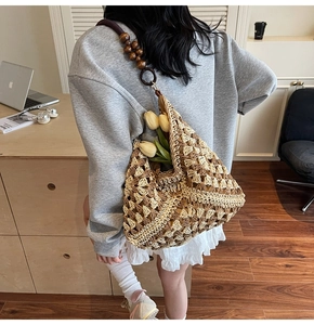 Detail of woven straw tote bag featuring mesh pattern and dark wooden bead strap