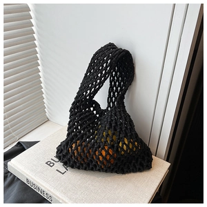 Detail of black crochet mesh tote bag showing capacity with oranges on a book