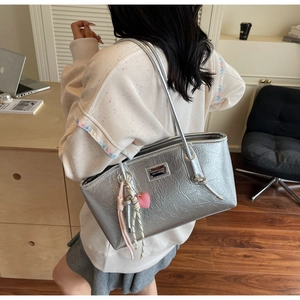 Silver metallic tote bag with crinkled texture and pink heart charm in daily setting