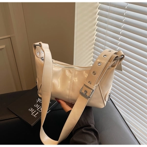 Dettaglio di una borsa sottobraccio beige lucida in pelle PU con fibbia in metallo e tracolla