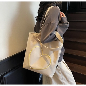 Détail d'un cabas minimaliste en toile avec broderie coeur jaune et bandoulière robuste