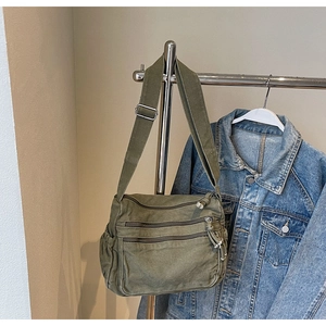 Detail view of military green canvas crossbody bag with multiple front zipper pockets