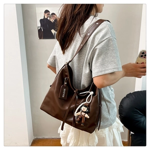 Detail view of large dark brown leather hobo bag with wide strap and clown charm