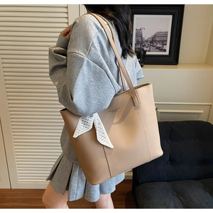 Close-up of khaki leather tote bag featuring lychee texture and white mesh ribbon bow