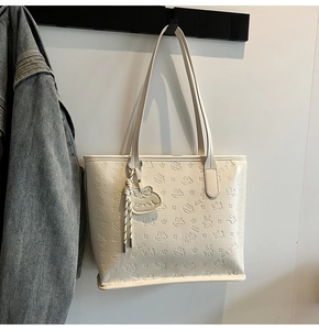 Détail du cabas crème avec gaufrage d'animaux et accessoire de sac assorti