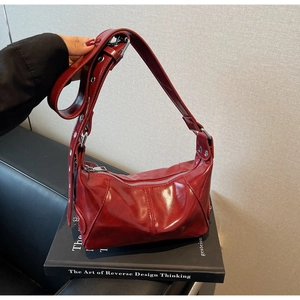 Dettaglio della borsa a spalla in vernice rossa lucida con fibbie in metallo argentato
