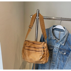 Detail of tan canvas crossbody bag with multiple zipper compartments and adjustable strap