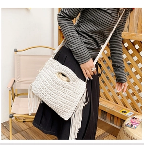 Detail of white crochet shoulder bag featuring fringe tassels and woven hollow handle
