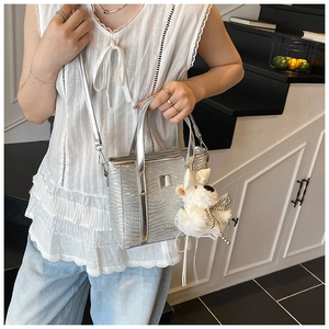 Silver sequined bucket bag with a plush bunny charm and a sleek crossbody strap