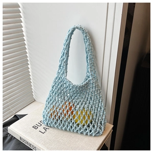 Detailed close-up of light blue hollow out knit handbag with texture on books