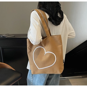 Détail d'un sac cabas en toile marron avec contour cœur blanc porté par un mannequin