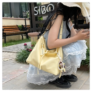 Detail of light yellow soft leather tote bag with pearl pendant on wooden bench