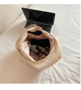 Dettaglio dell'interno capiente della borsa tote beige plissettata con oggetti personali